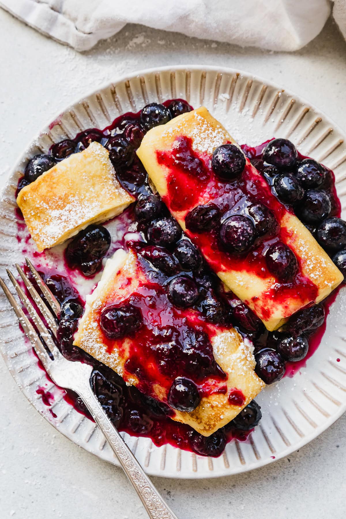 Cooked cheese blintzes on plate with blueberry sauce