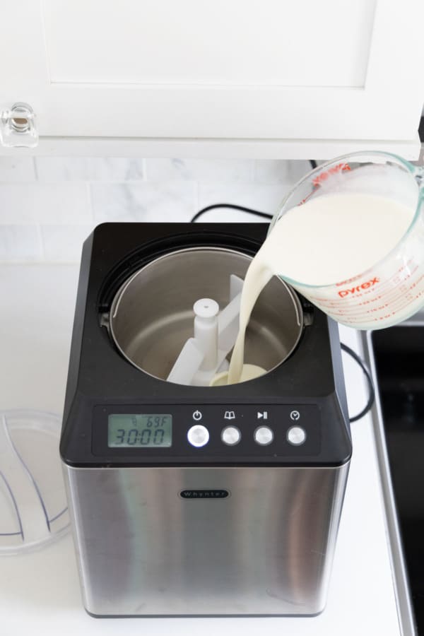Pouring liquid popcorn ice cream base into an ice cream machine.
