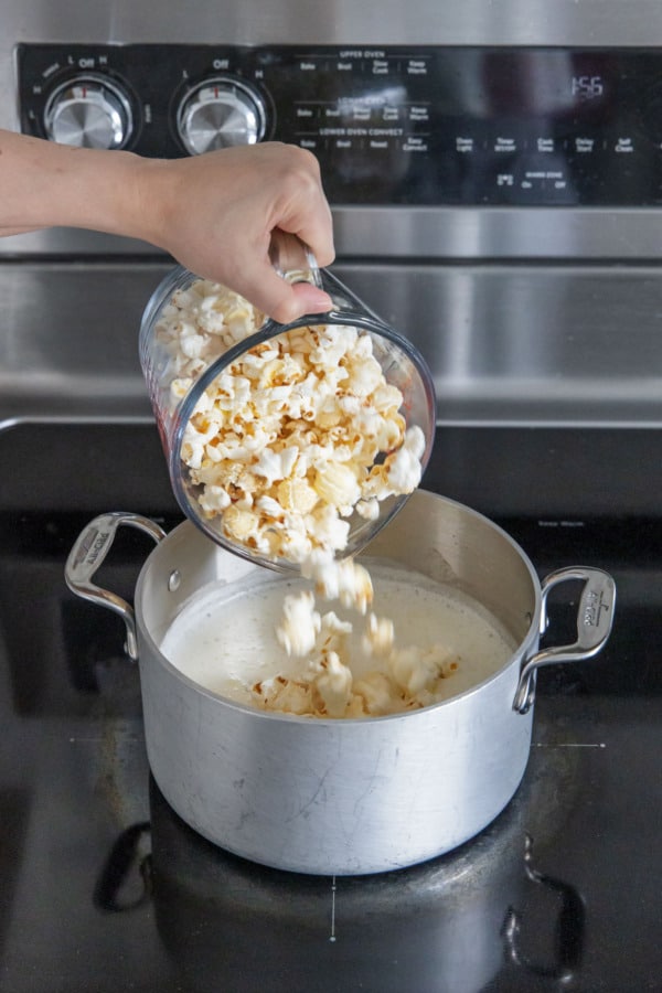 Pouring 4 cups of popcorn into warm ice cream base.