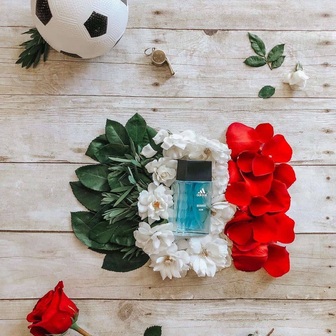 a bottle of adidas moves him cologne on top of flowers and leaves