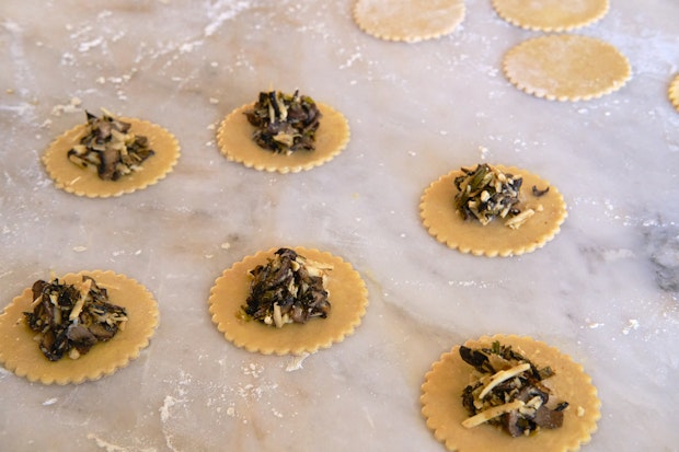 pie dough rolled out on a marble counter with a wood rolling pin
