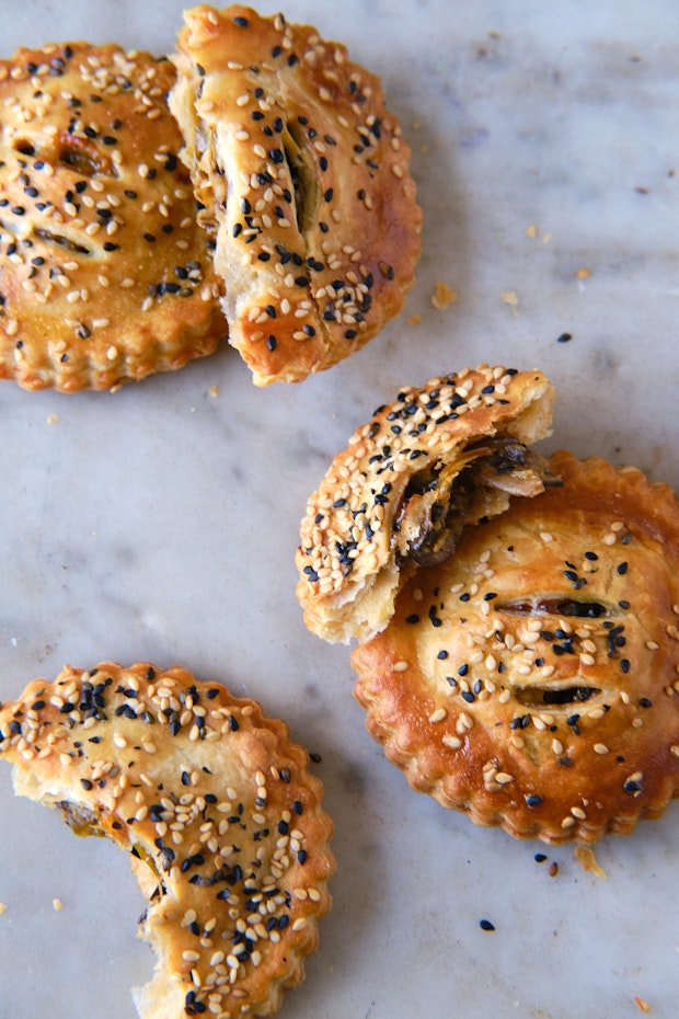 pie dough rolled out on a marble counter with a wood rolling pin