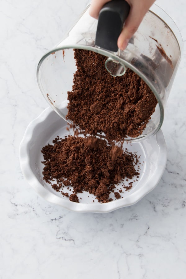 Pouring the chocolate graham cracker crumb mix into the pie pan.