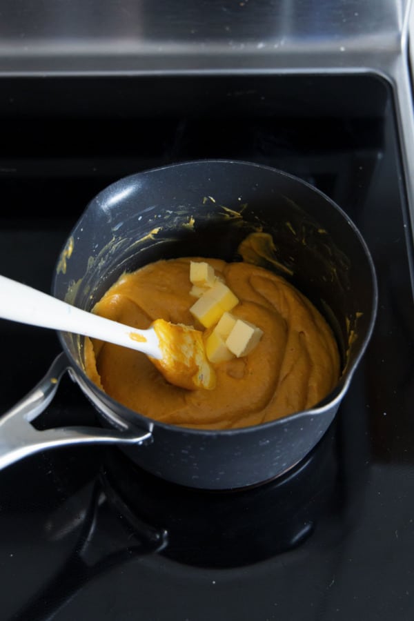 Adding small cubes of butter to cooked custard off the heat.