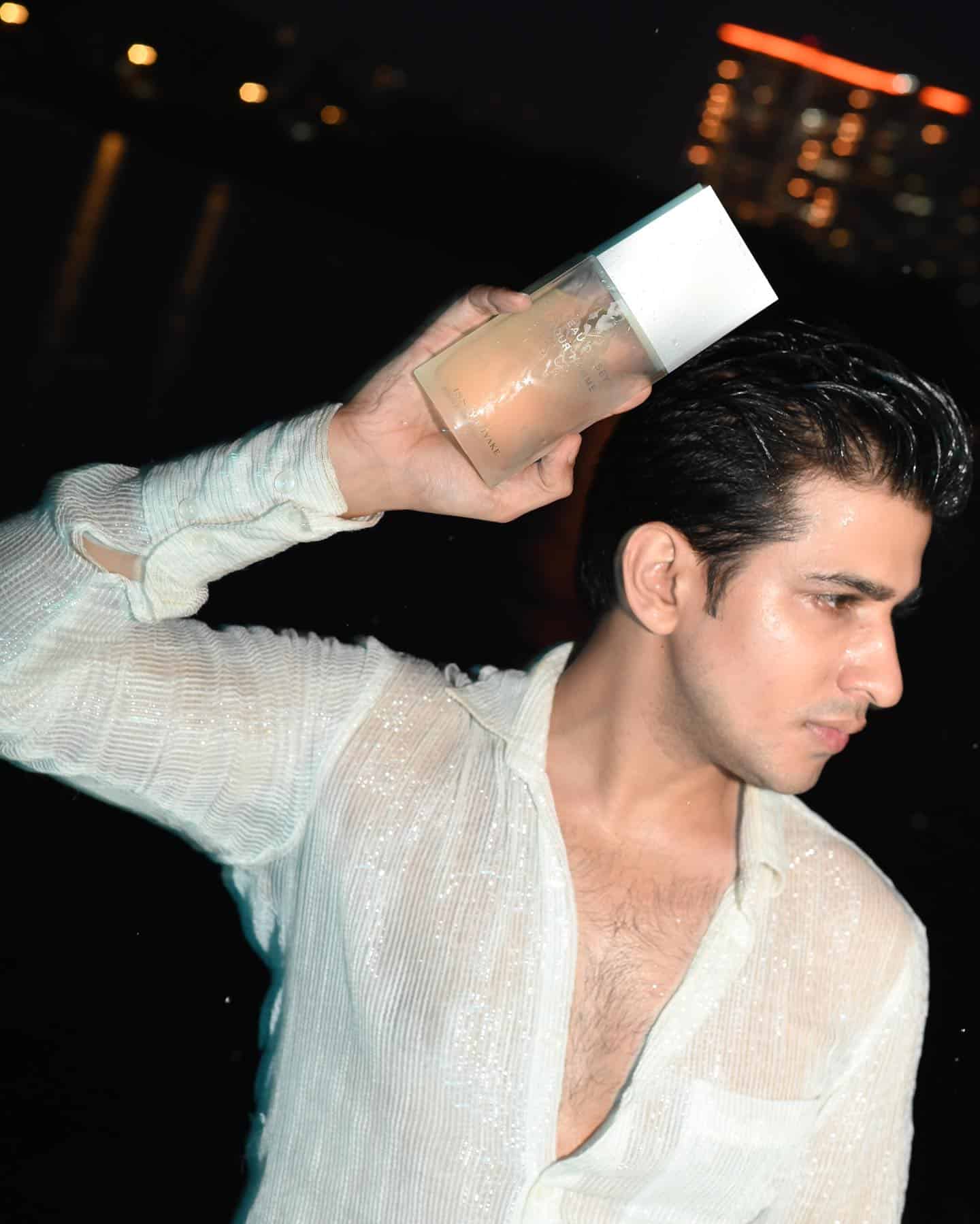 man holdingup a bottle of l'eau 'dissey pour homme by issey miyake